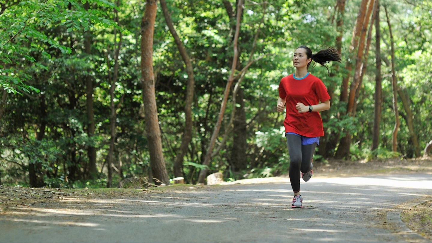 A woman running in eco-friendly fitness apparel in the woods