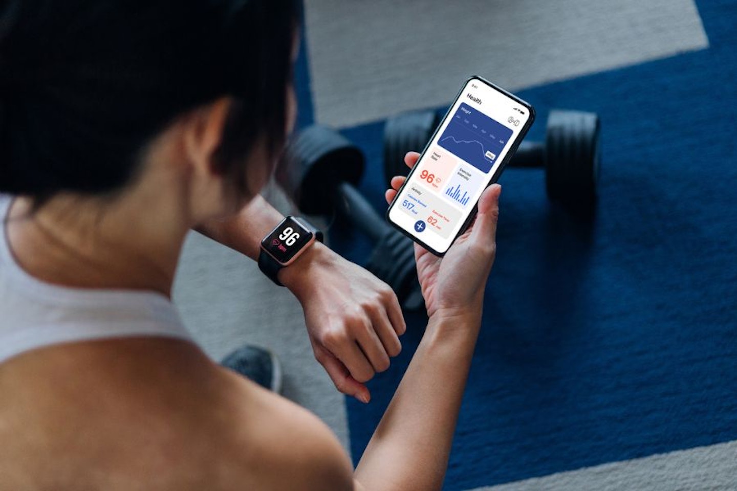 A man looking at his smartwatch and his phone after exercise