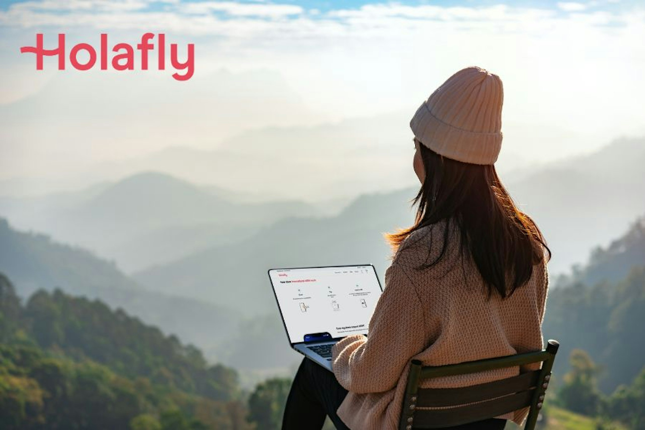 A woman sitting on a mountain on holiday using a laptop - Holafly eSIM