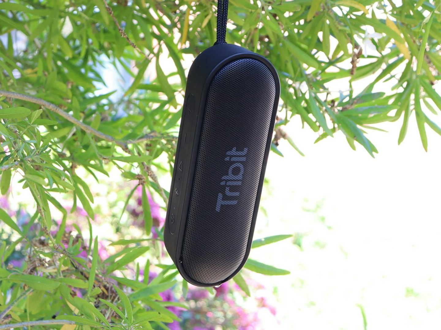 Tribit XSound Go portable wireless speaker hanging on lanyard in a tree