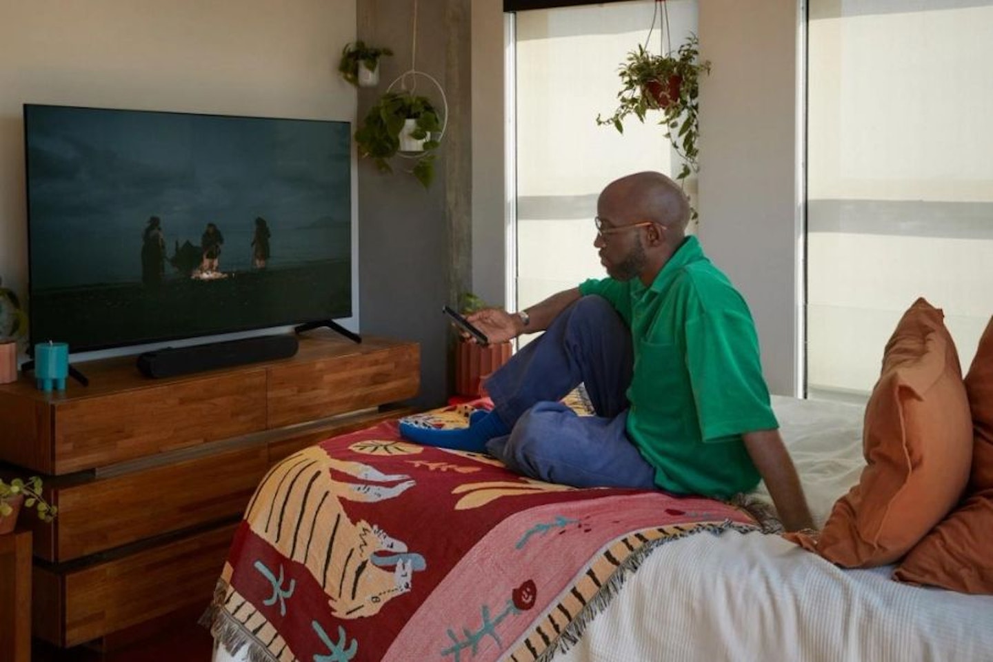 A man sitting on a bed surrounded by his Sonos home sound system