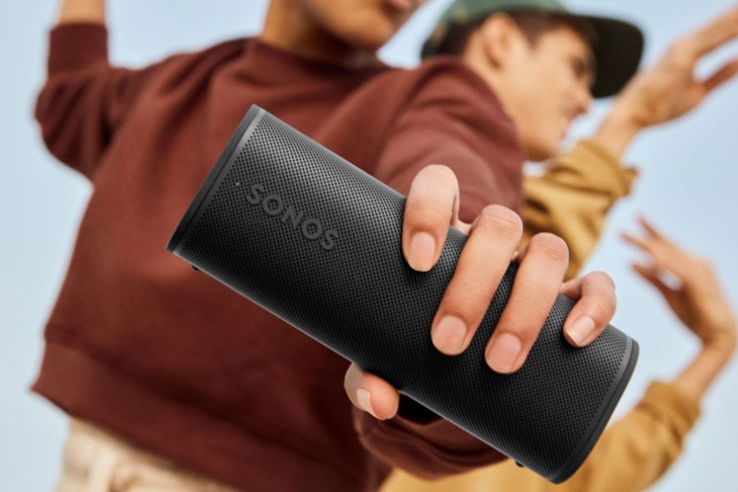 Two men dancing, one of them holding the Sonos Roam 2