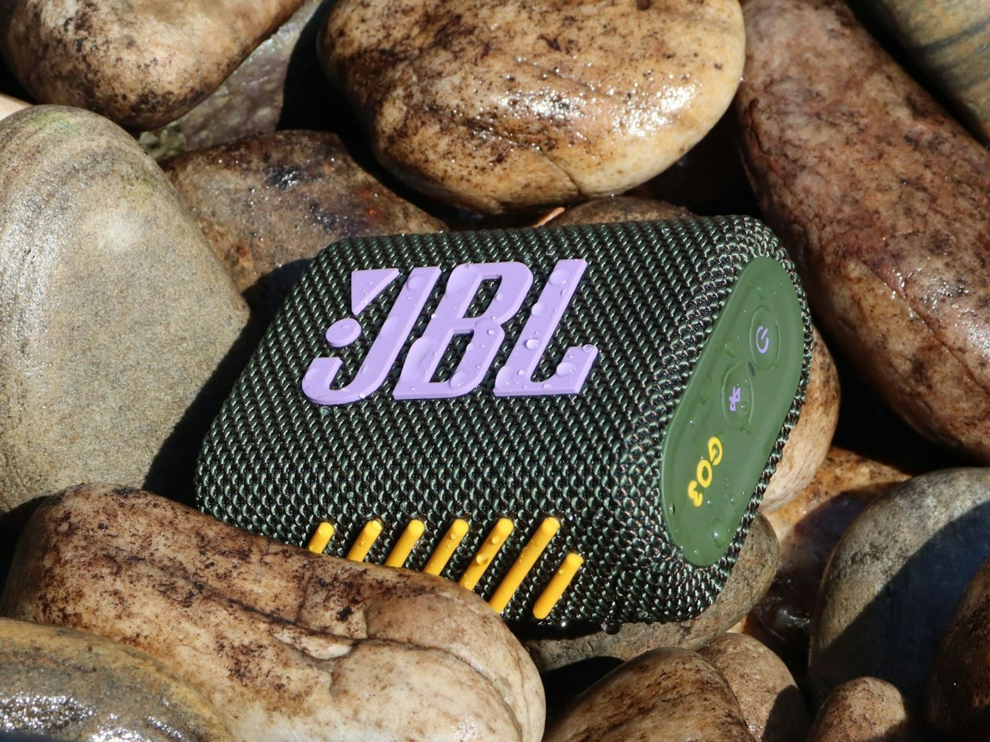 JBL Go 3 Bluetooth speaker on pebbles