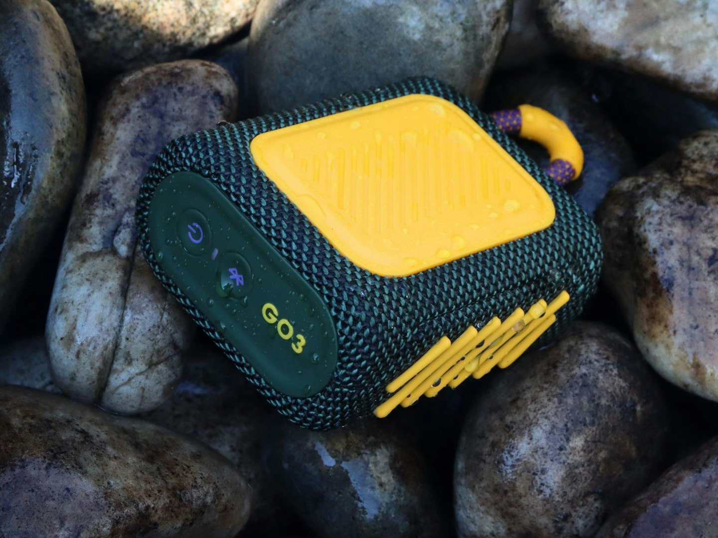 JBL Go 3 Bluetooth speaker on pebbles