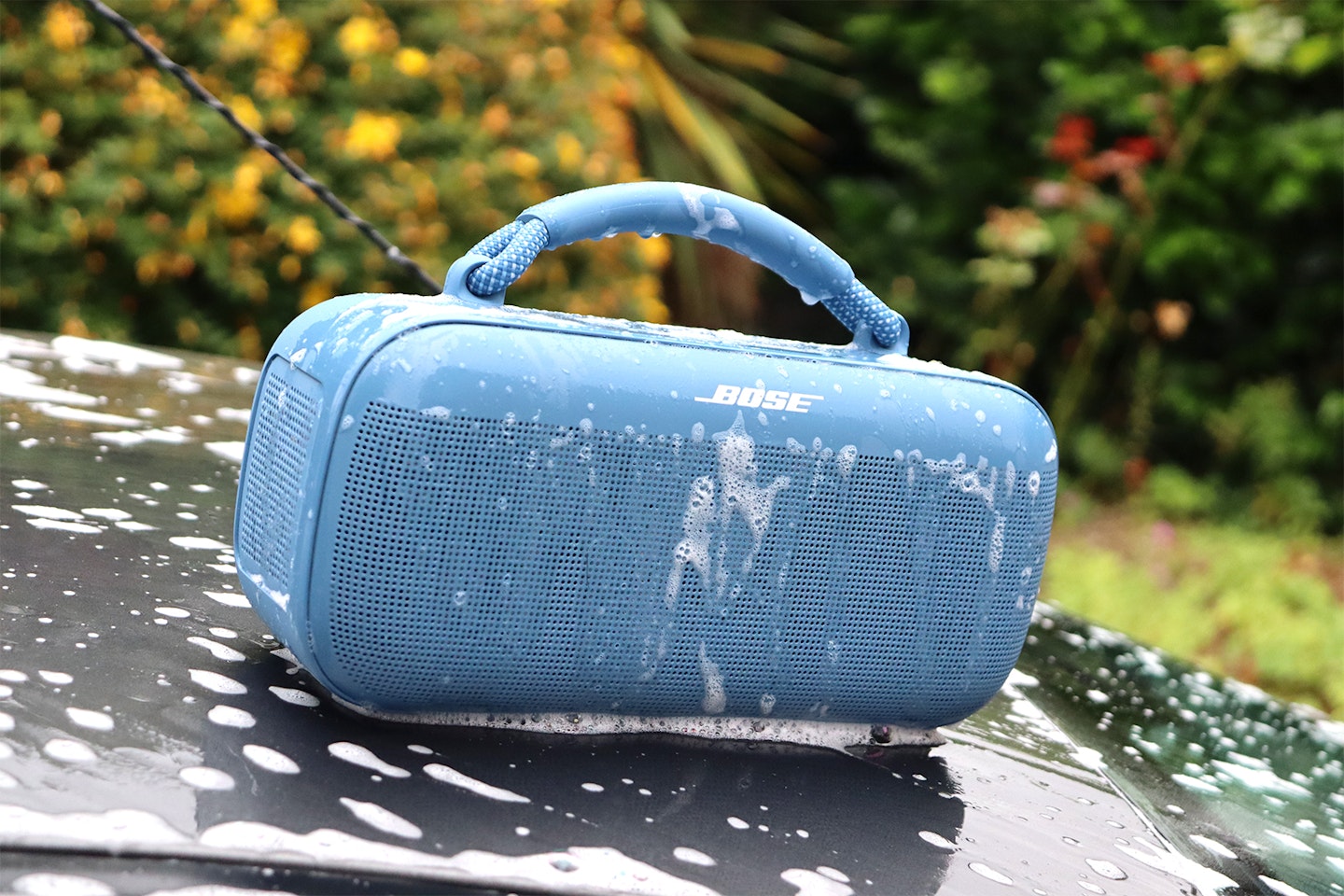 Bose Soundlink Max Portable Speaker on a car roof being washed