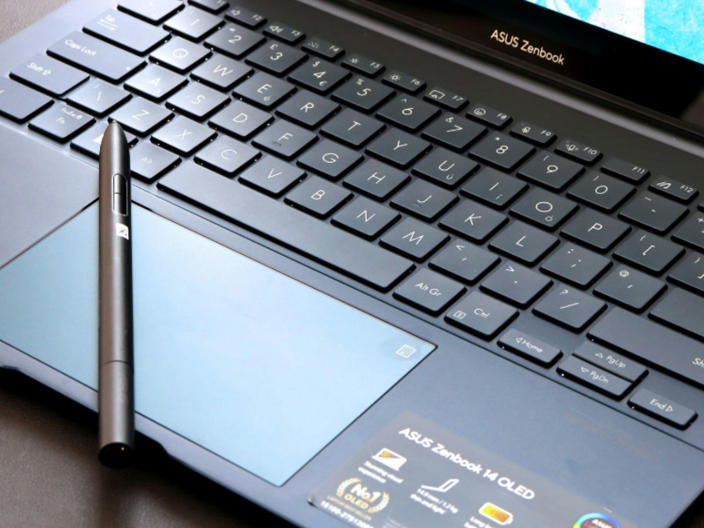 An ASUS laptop keyboard, touchpad and stylus