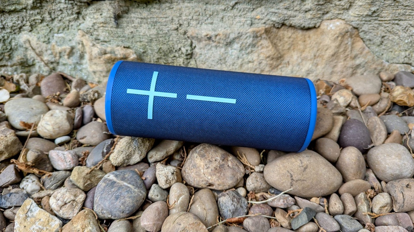 UE Boom 4 speaker lying on some pebbles