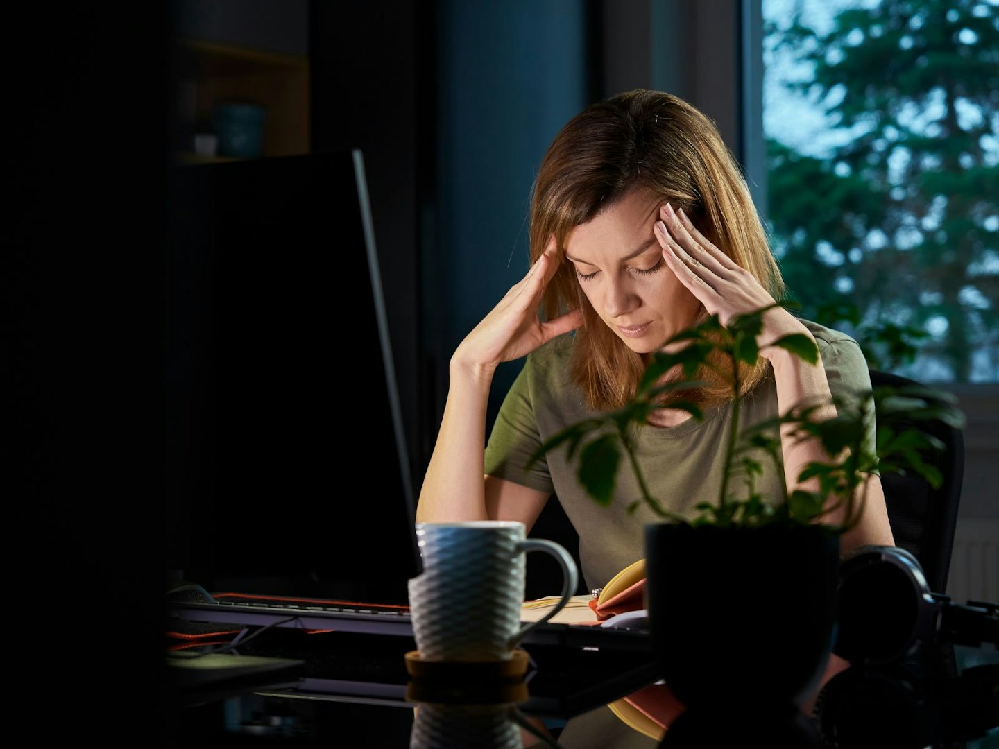 someone with a headache sitting at a computer monitor