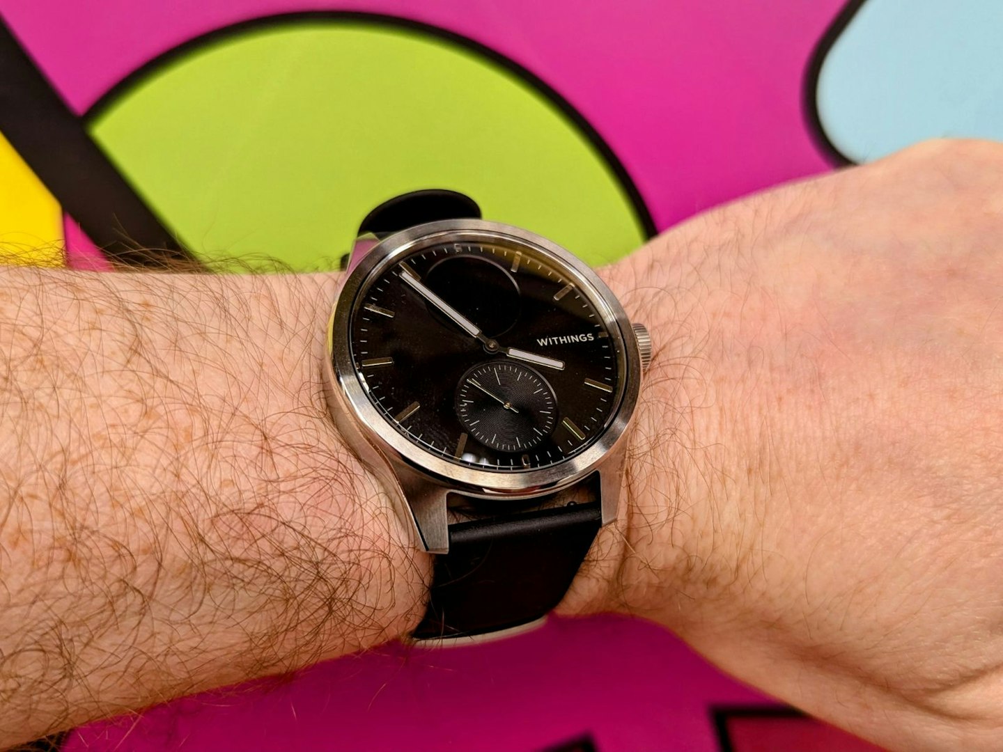 Withings ScanWatch 2 on wrist, graffiti wall in background