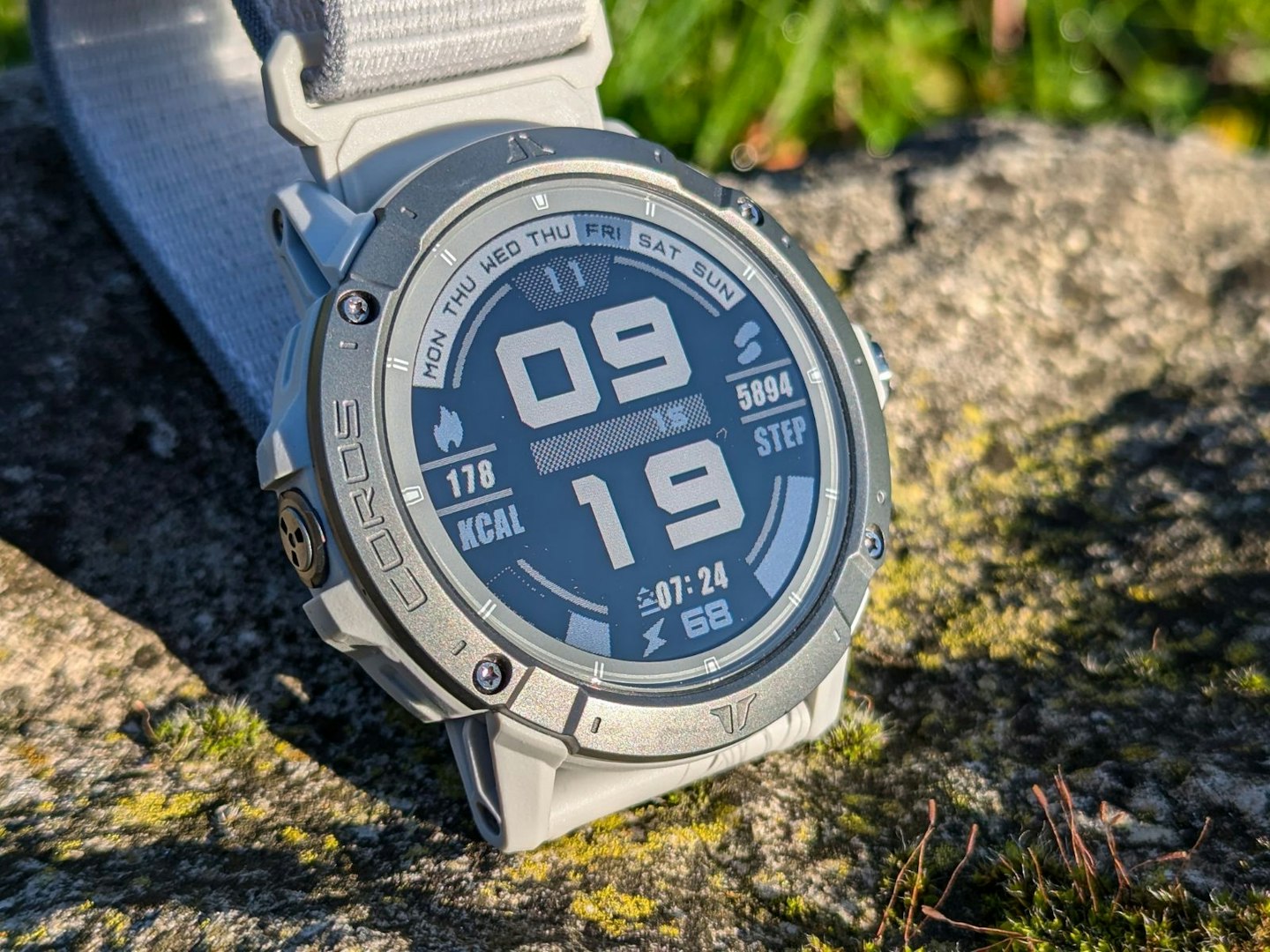Coros Vertix 2S on a mossy rock, bathed in sunlight