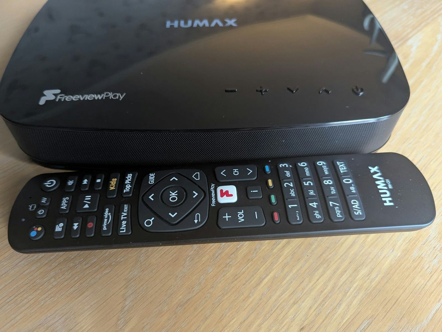 HUMAX Aura Android TV 4K Freeview Play Recorder with Google Assistant and Chromecast. One of the best Freeview boxes. Box and remote on table.