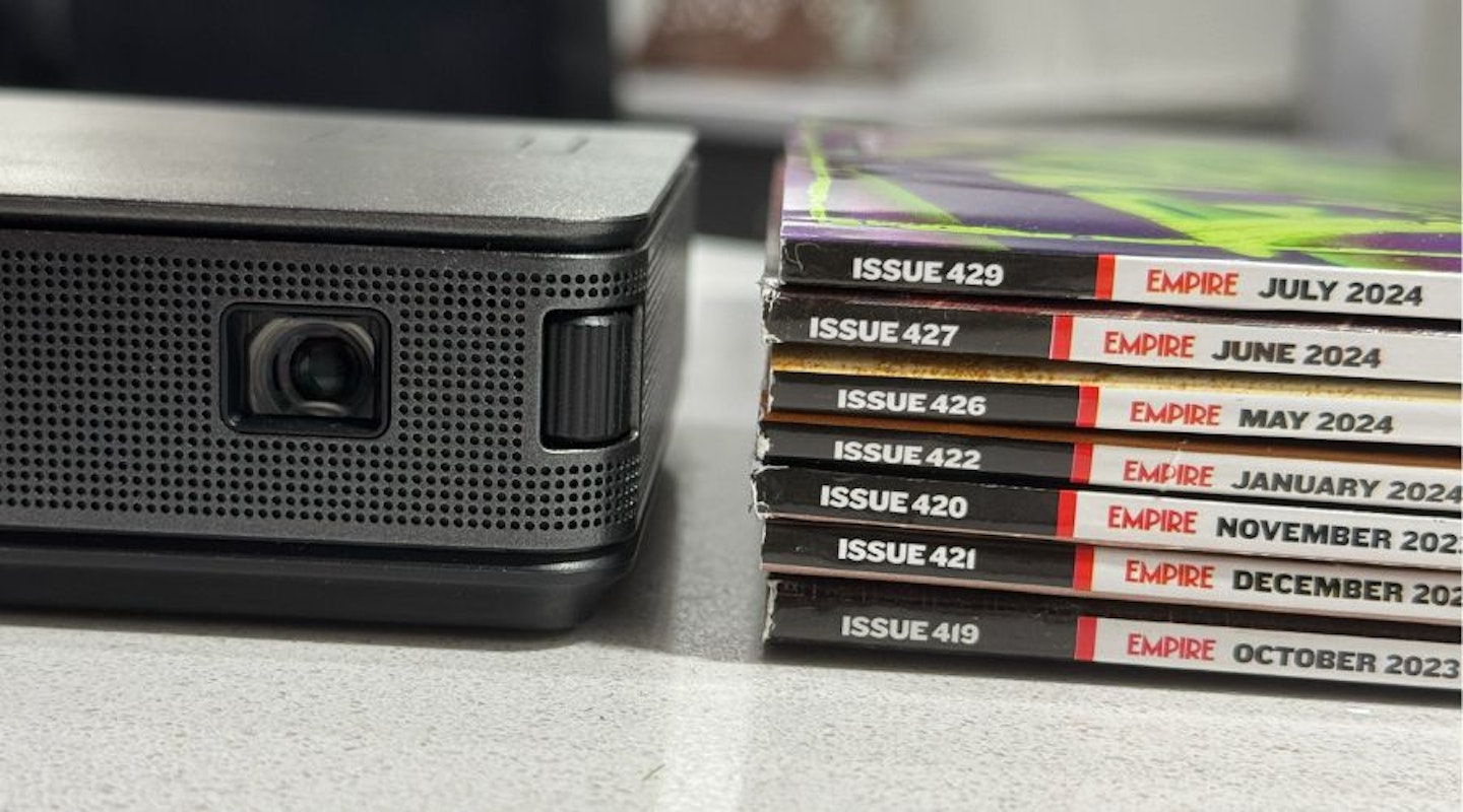 AOPEN Fire Legend PV12a LED Projector - device seen from the front next to a pile of Empire film and TV magazines