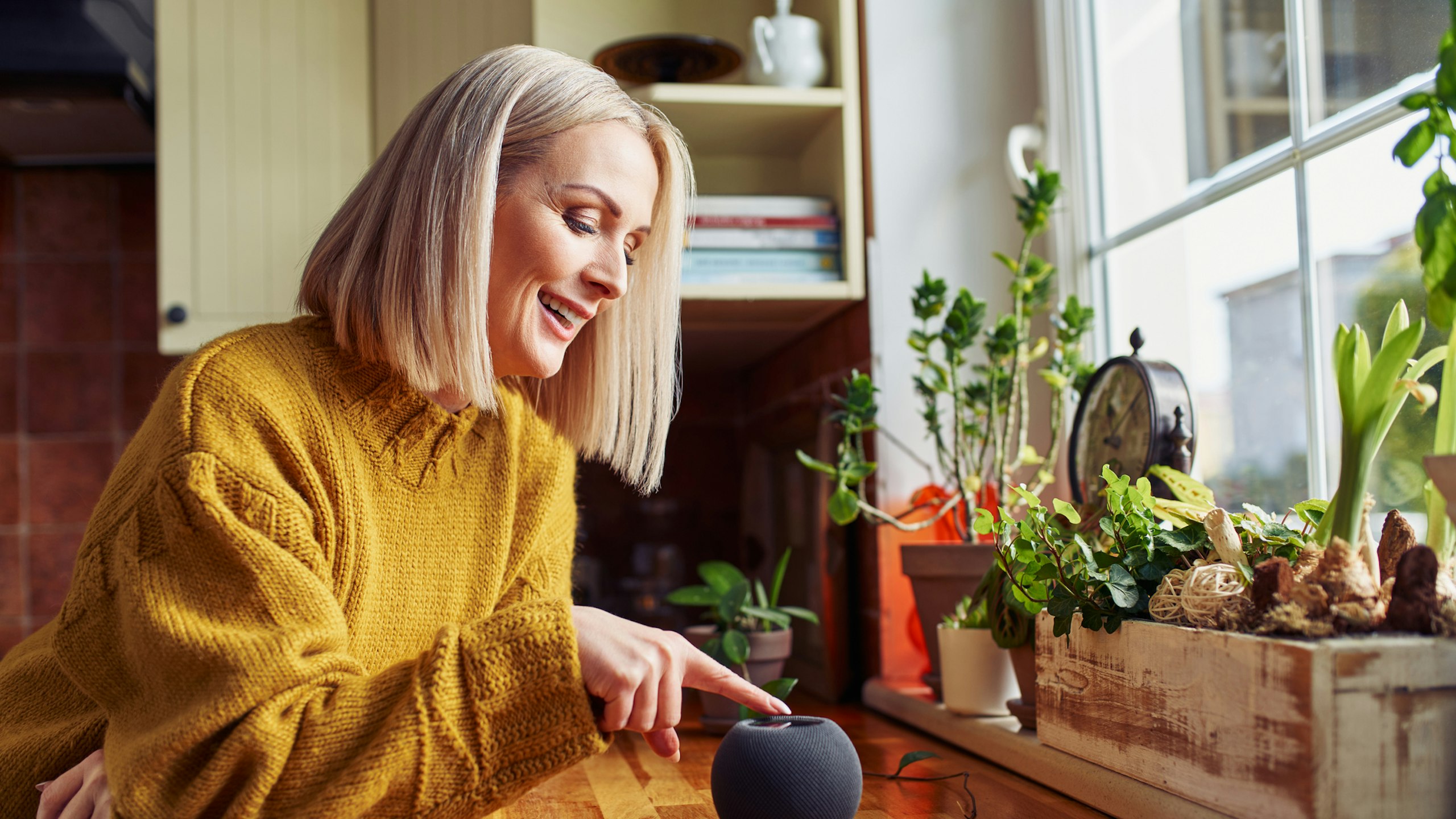 Happy mature woman using smart speaker at home