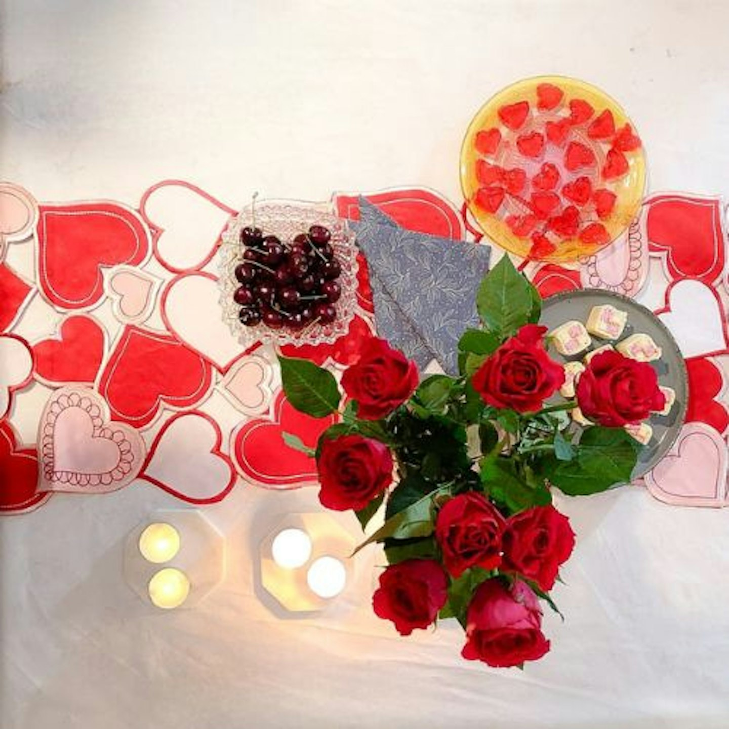 Top view of the Simhomsen Embroidered Love Heart Table Runner with roses, candles, cherries, cake and jelly hearts