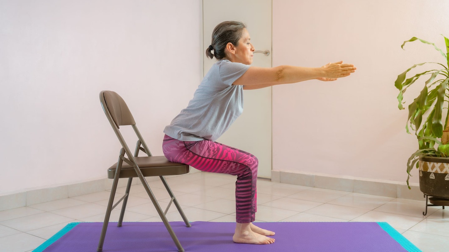 Woman doing a squat to a chair