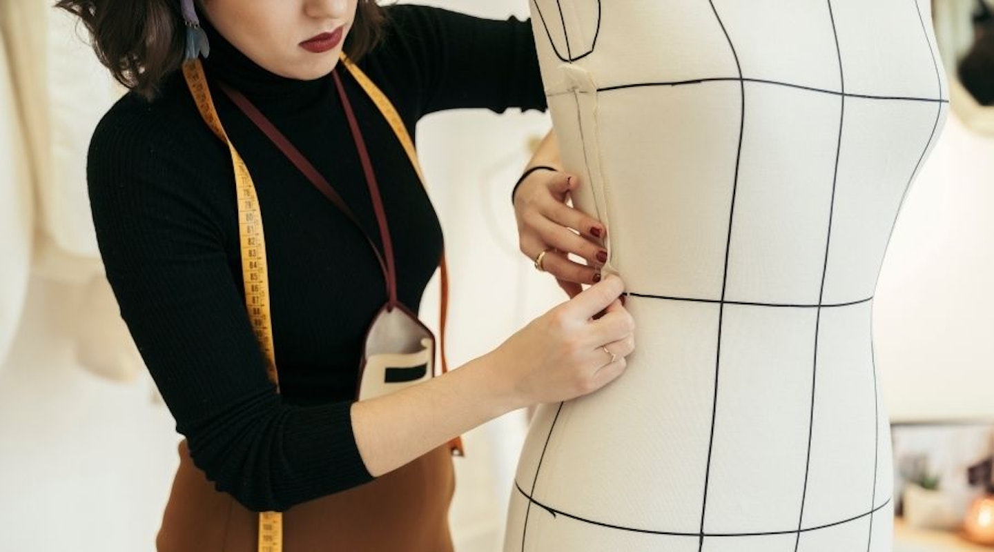 A woman pinning fabric onto a dressmaker mannequin