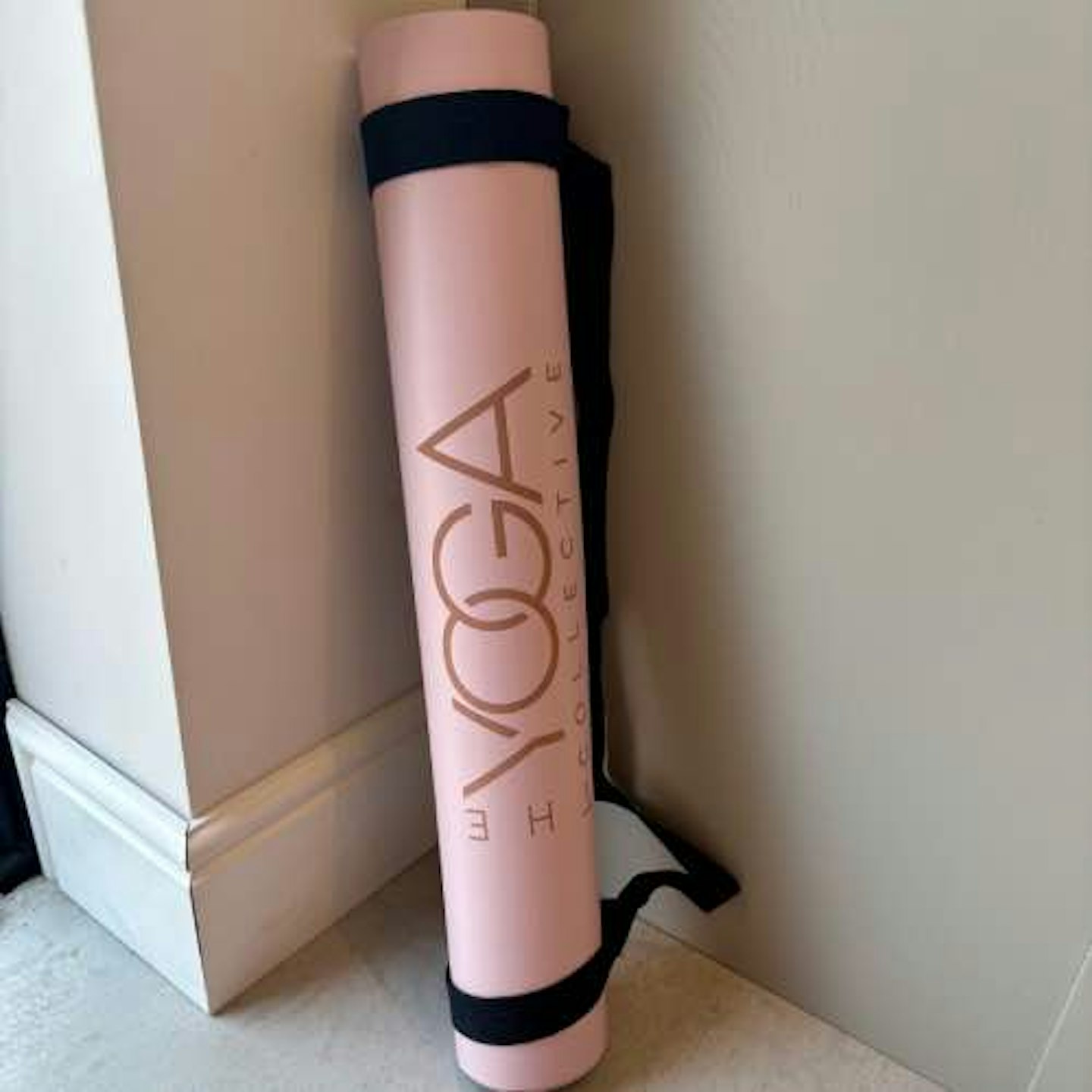 Pink yoga mat rolled up standing against a wall 