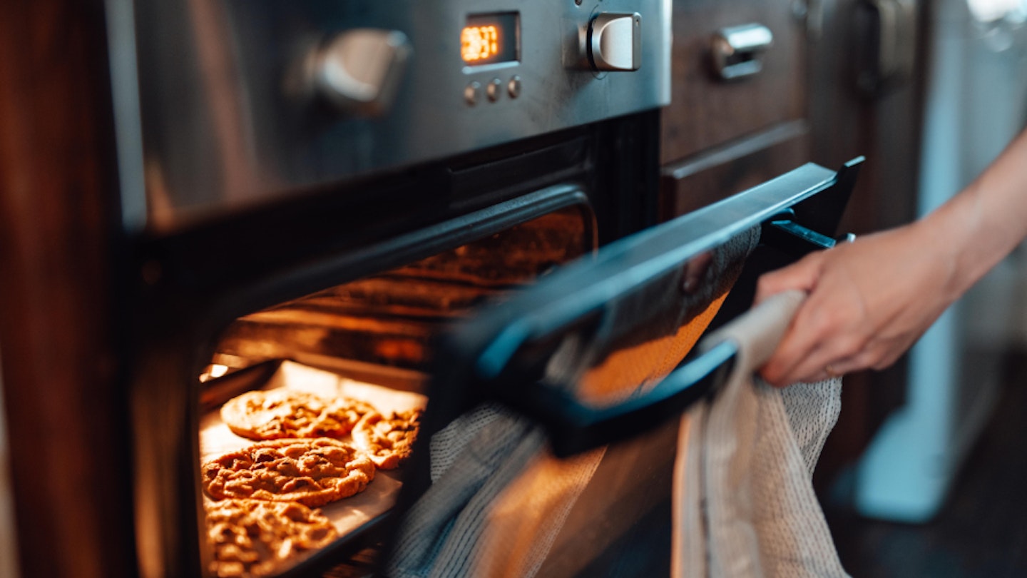 A person baking cookies in multifunctional oven