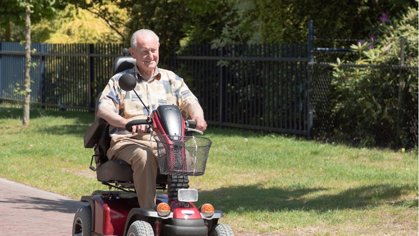 An elderly man driving a mobility scooter