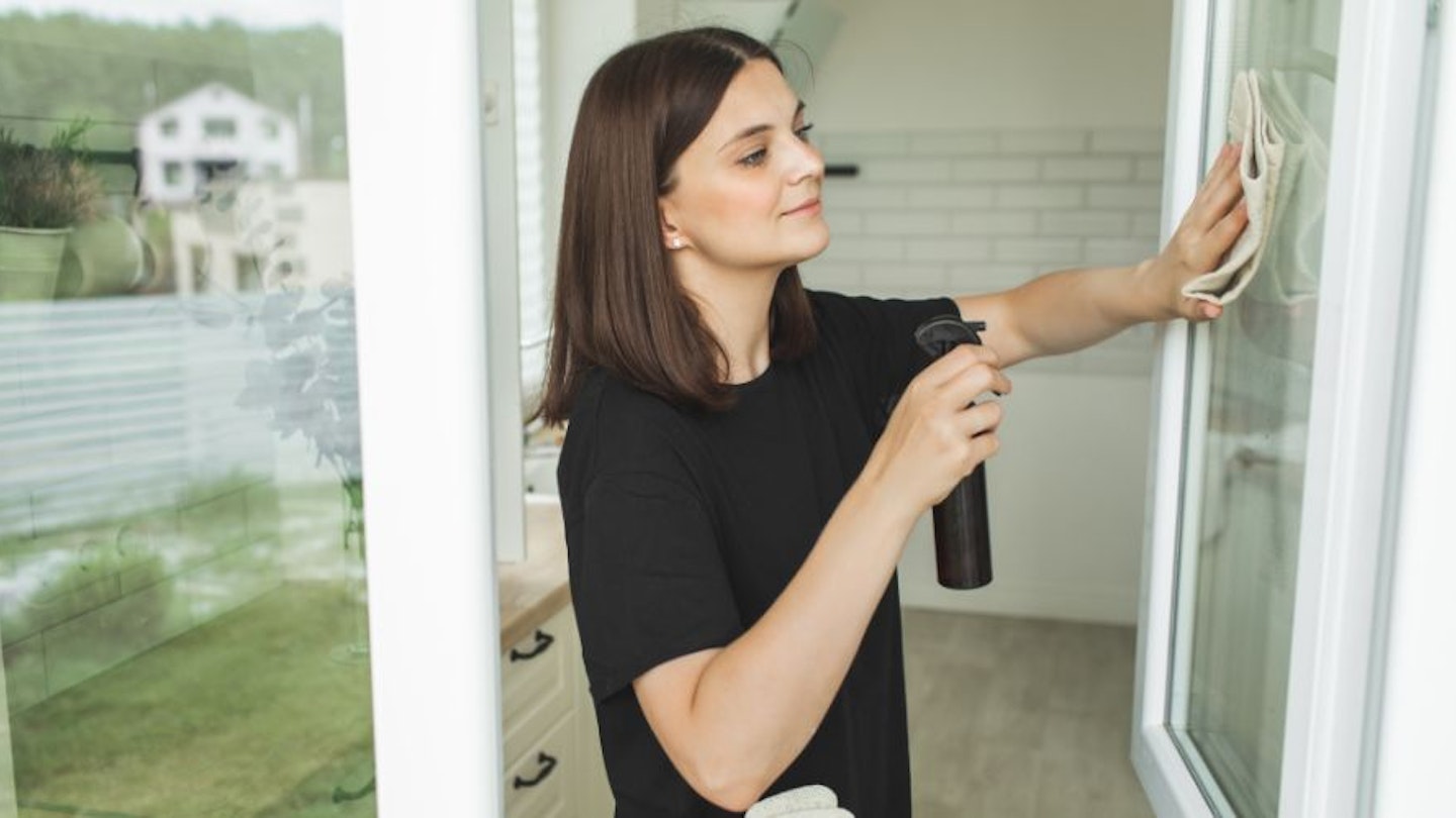 A woman using plastic-free cleaning products to clean her windows