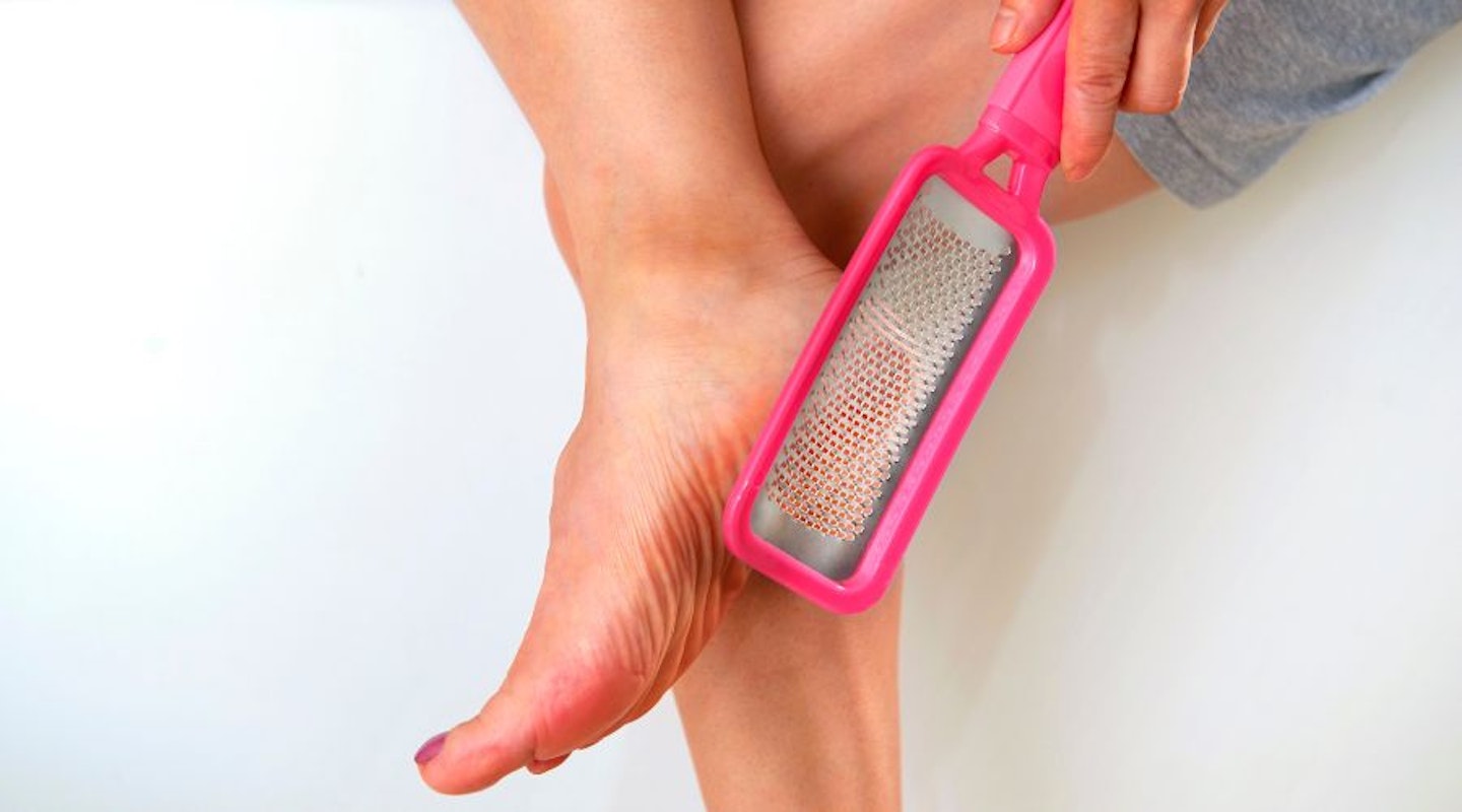 A woman using a foot file from a pedicure set to get hard skin off her feet