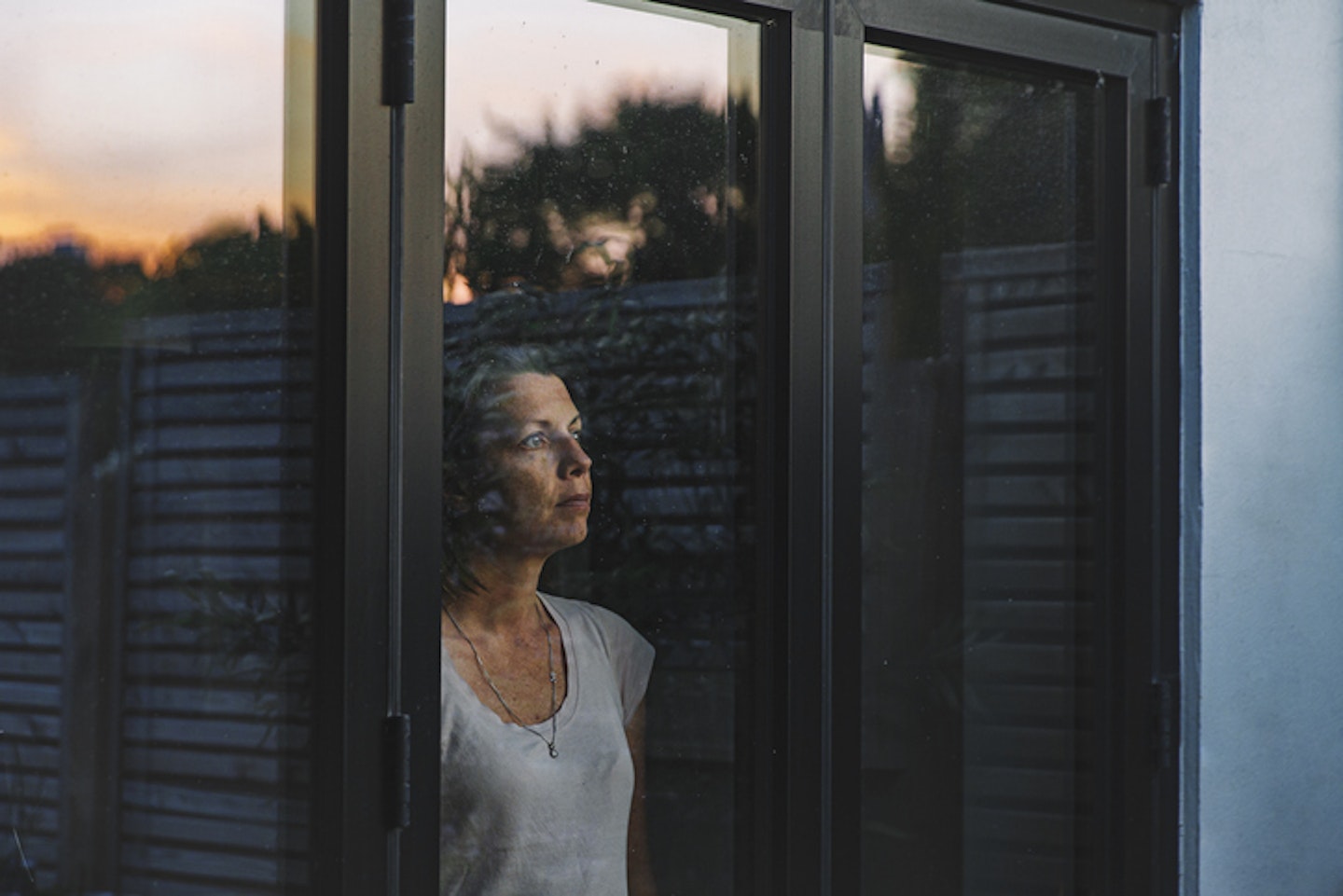 Woman looking through window at dusk