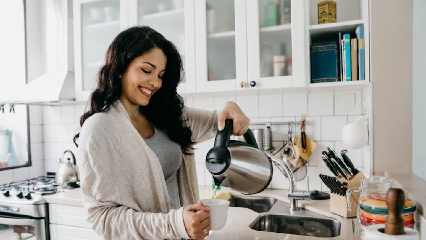woman pouring from a kettle in kitchen