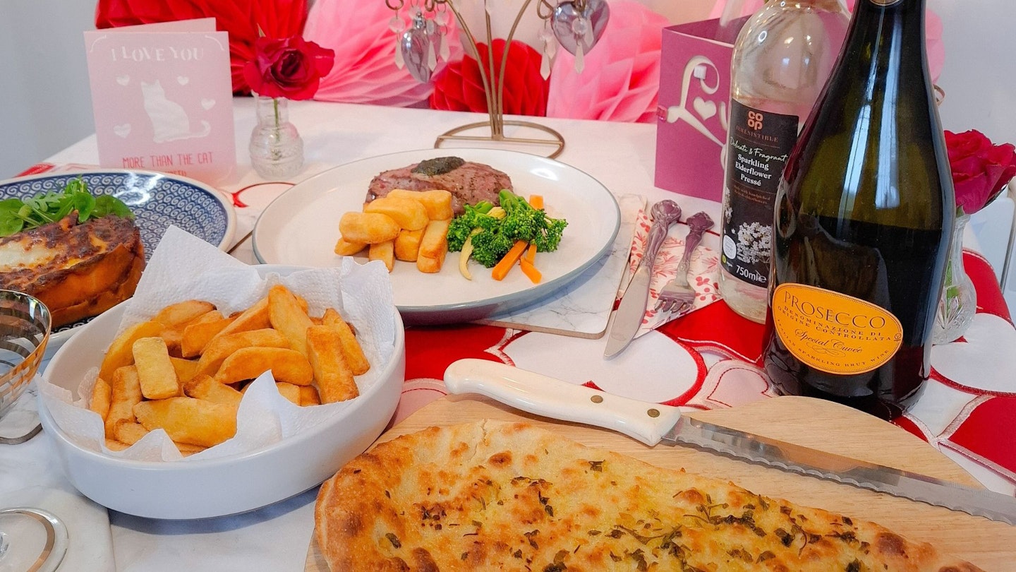 Valentine's table with Co-Op meal deal chips, flatbread, steak, lasange, prosecco and elderflower presse.