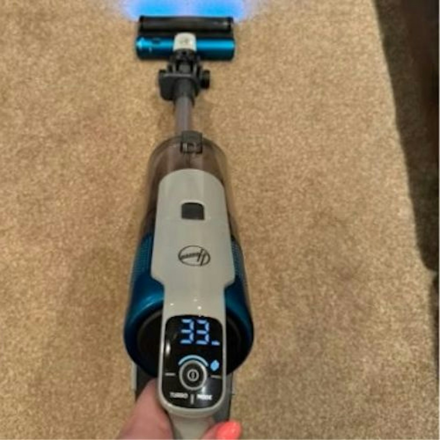 Hoover HF9 cordless vacuum being used on carpet, showing the LED headlights on the brush head