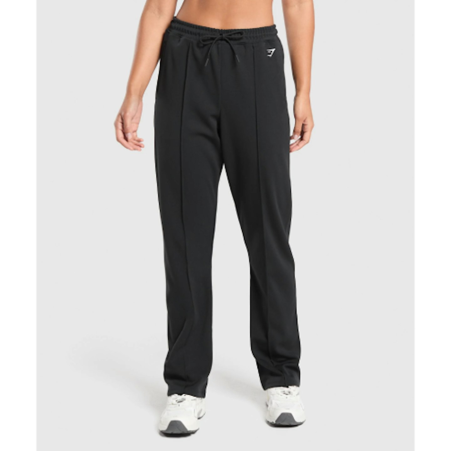 Gymshark tricot joggers, woman wearing a black pair of joggers and white trainers, pictured from the waist down 