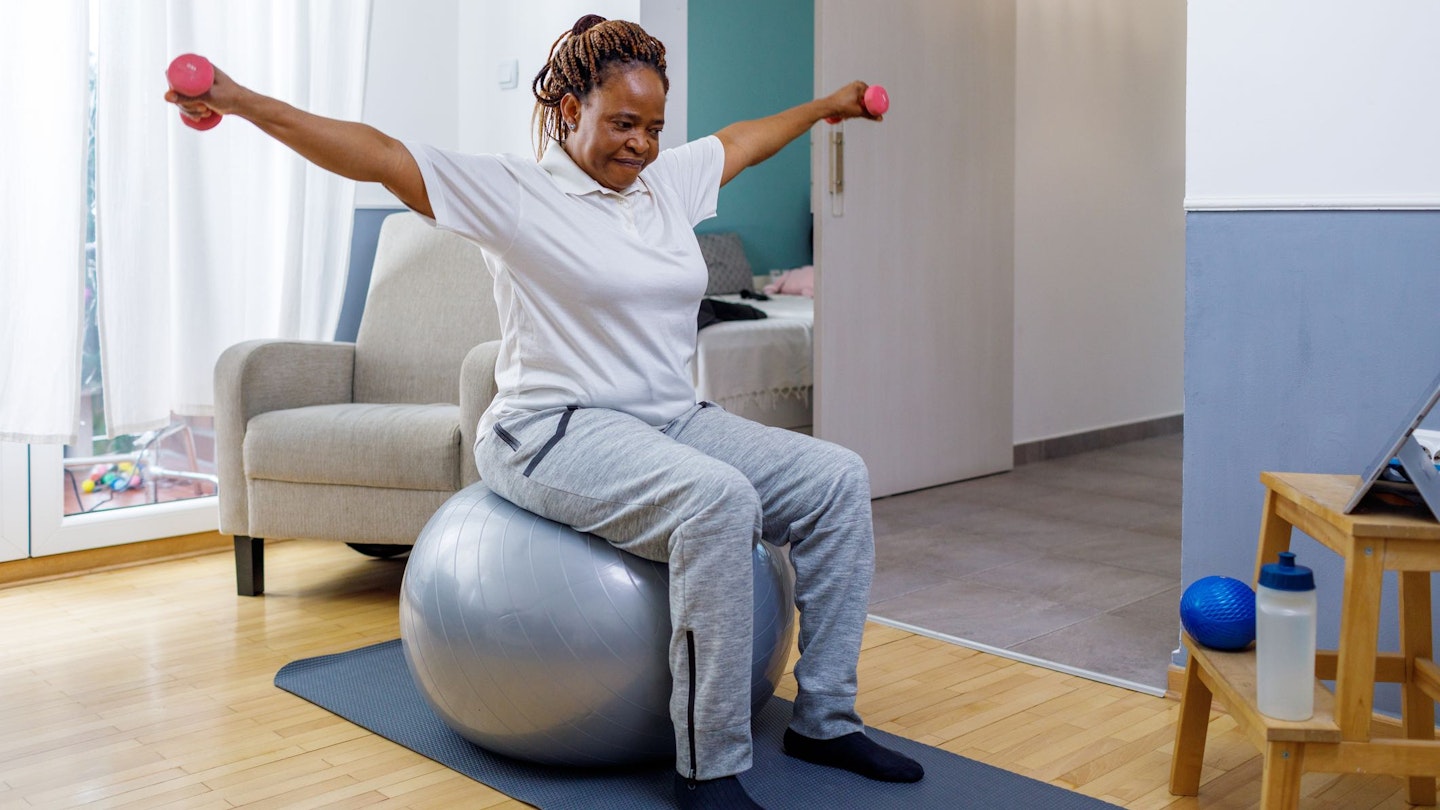 Woman sitting on an exercise ball to lift weights