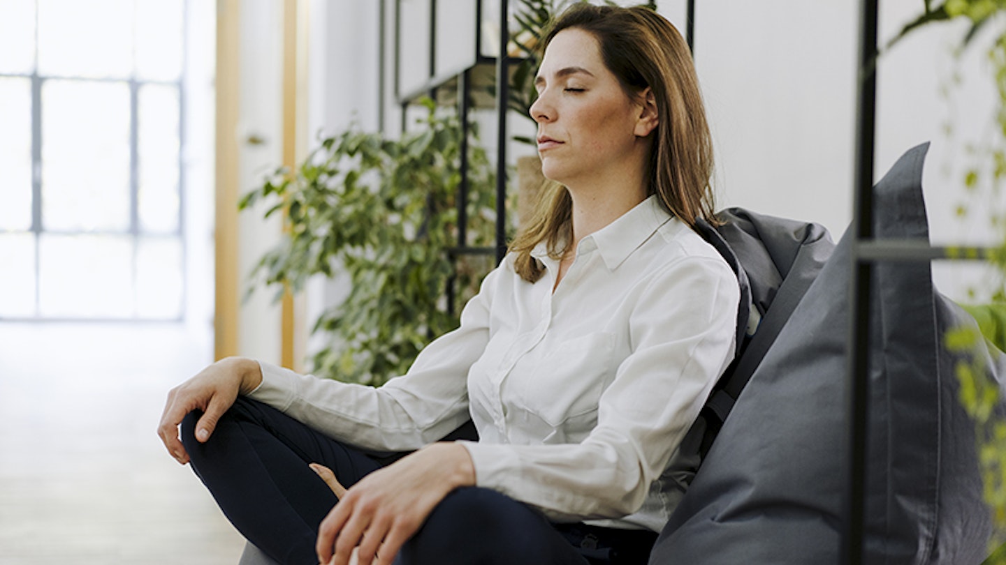 Woman practicing yoga while sitting on bean bag at office