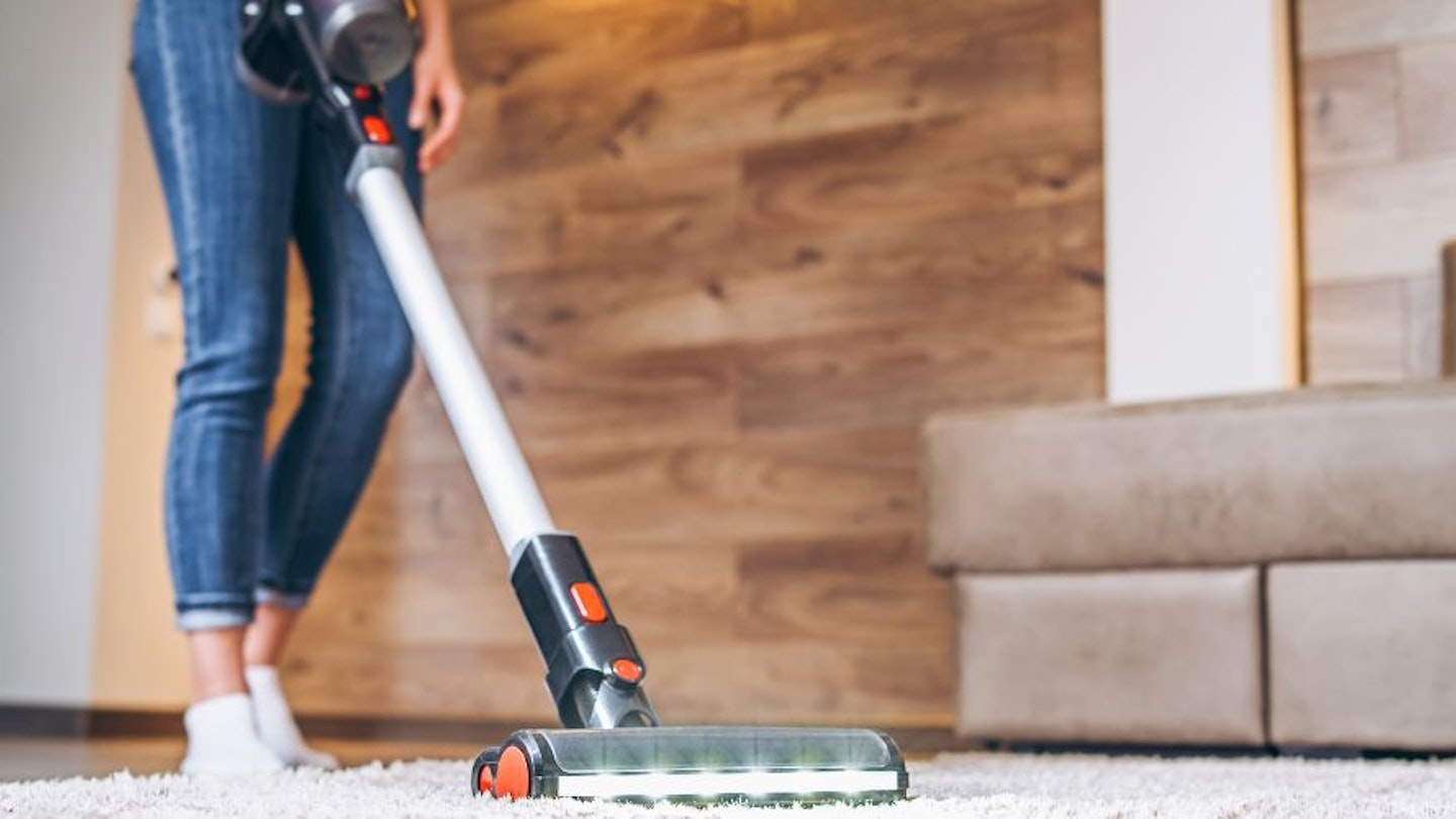 A woman cleaning her floors with a cordless vacuum cleaner