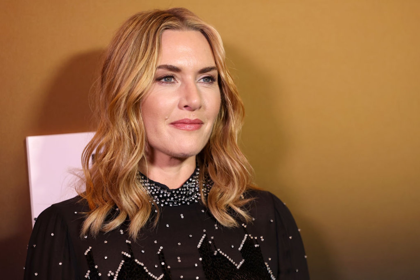 Photo of Kate Winslet with wavy hair and a black dress