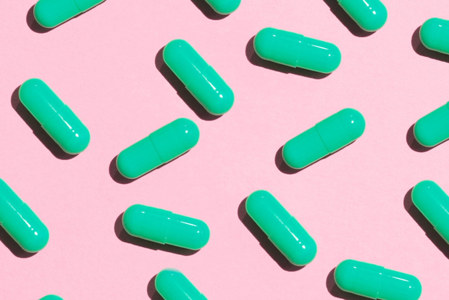 Green Pills On A Pink Colored Background