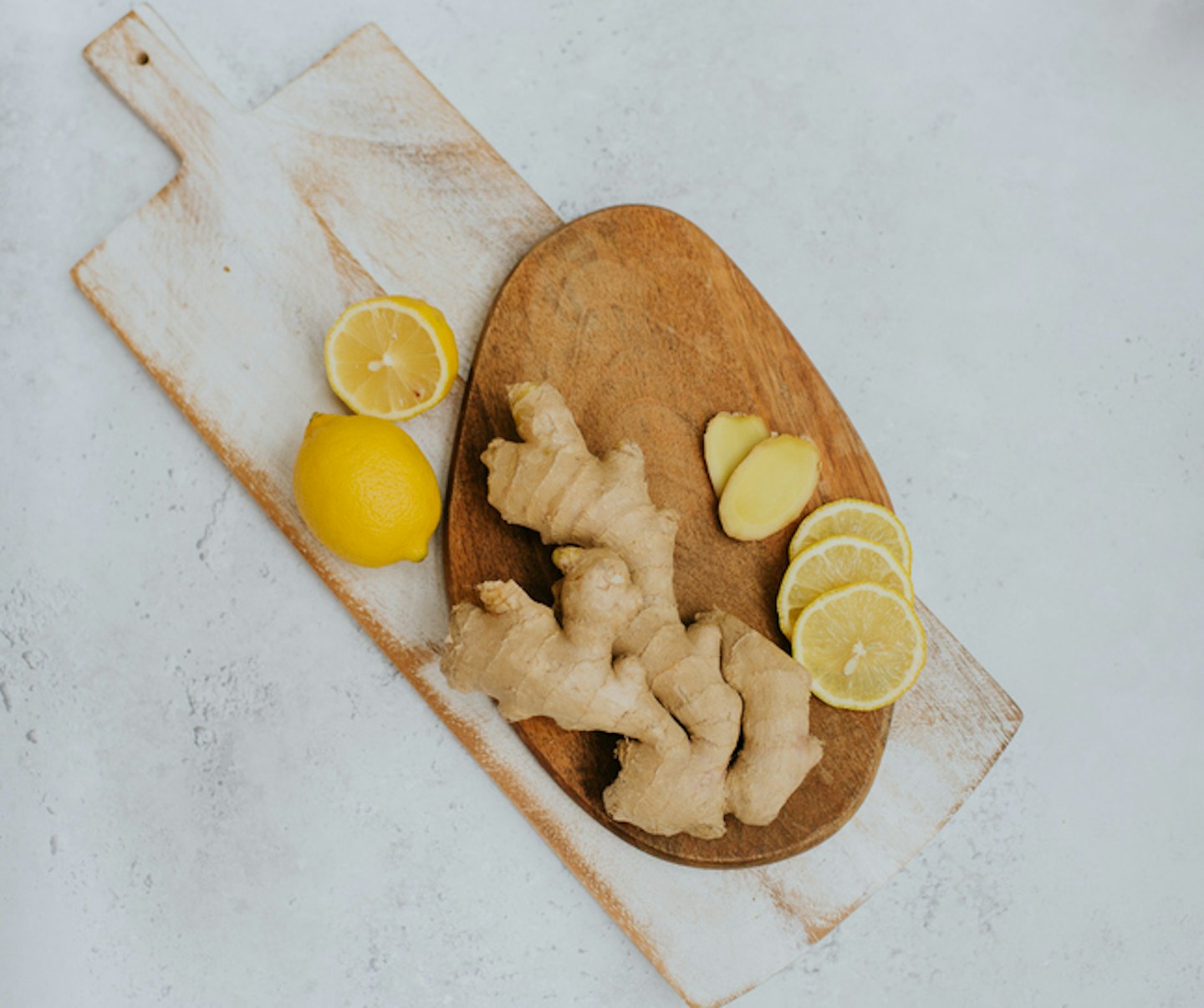 Top down image of whole ginger and lemons on two wooden chopping boards