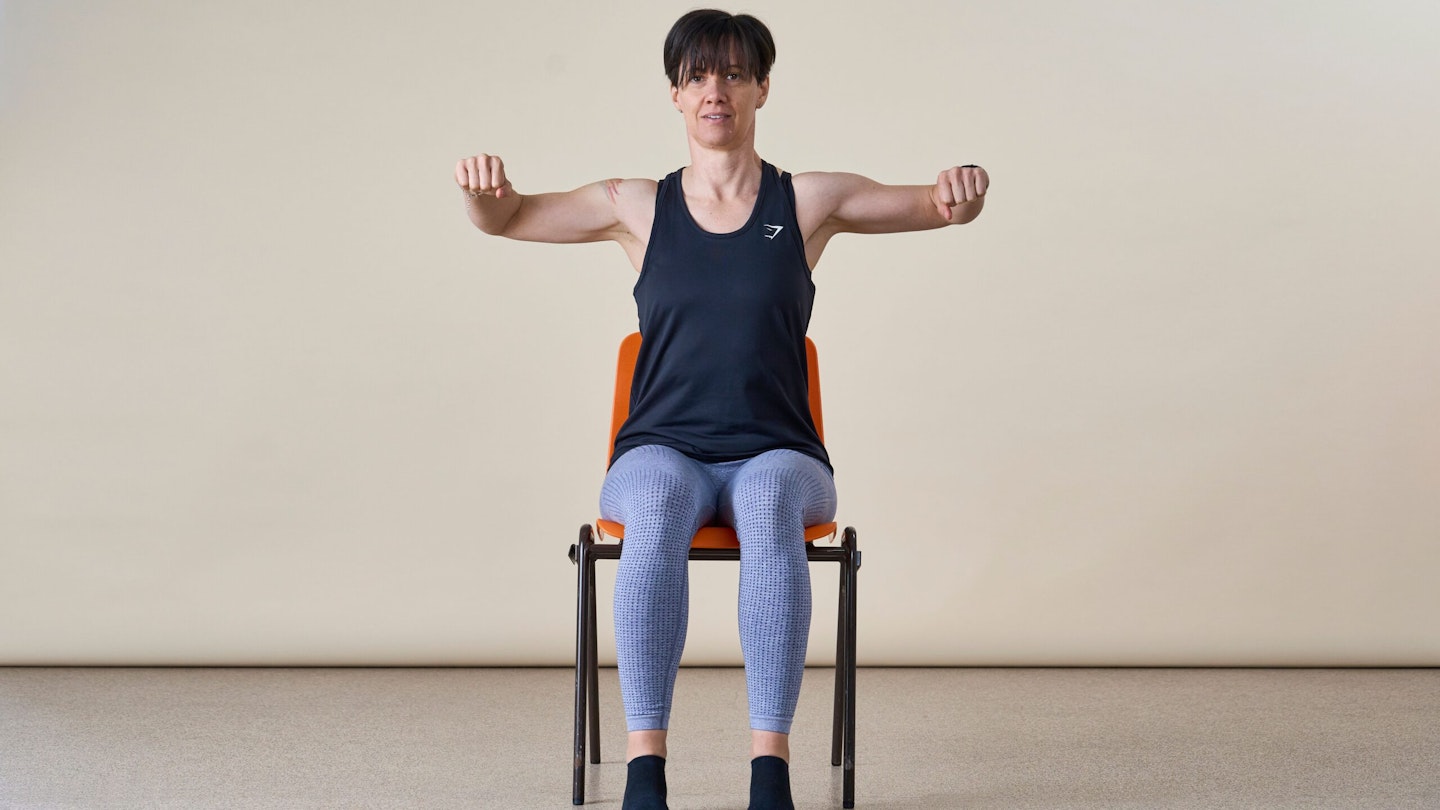 Woman facing camera doing a rowing action in a chair