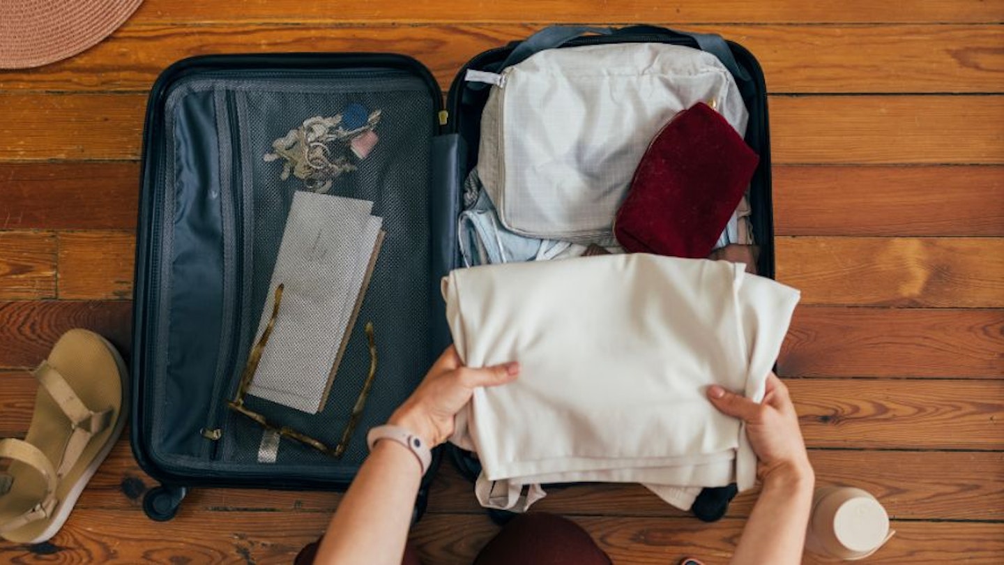 Best cabin bag: a woman packing a cabin bag for a holiday