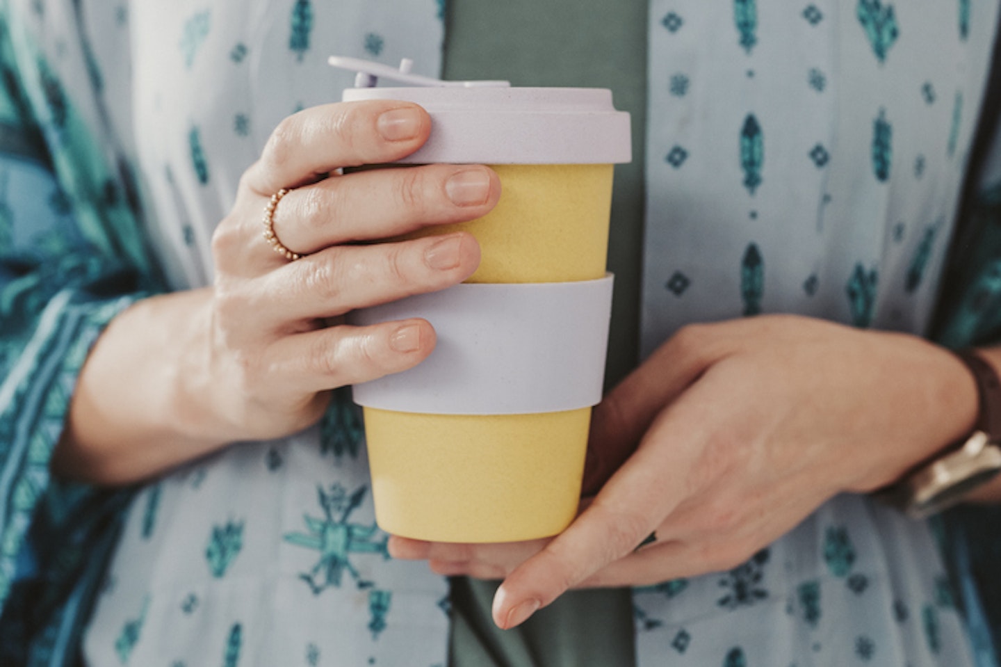 Woman holding to go take out coffee cup