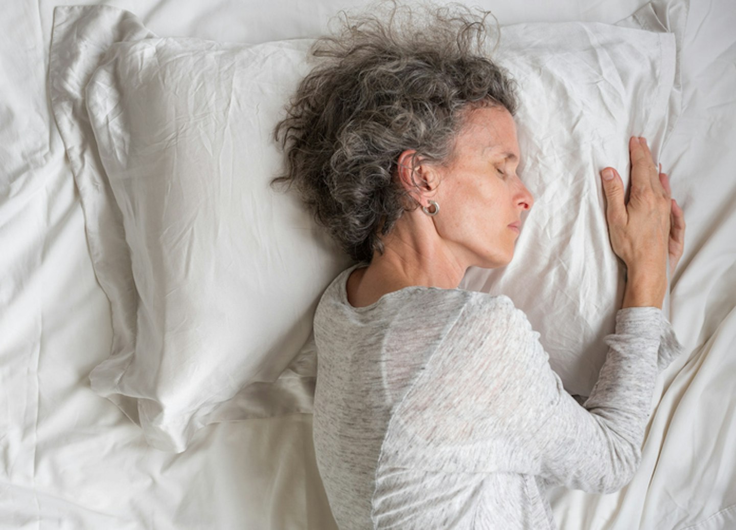 Middle aged woman sleeping on silk pillow case from above