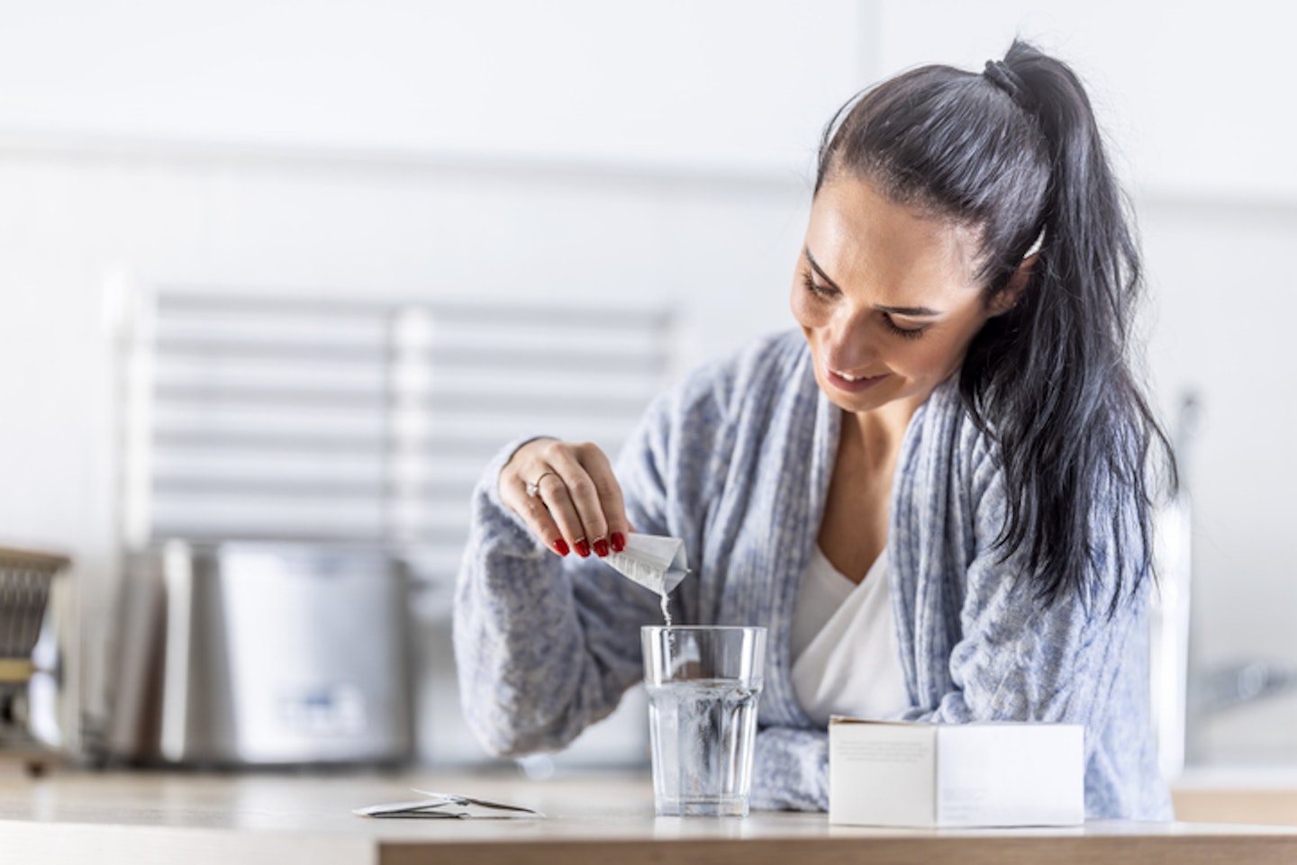 A young woman pours magnesium nutritional supplement into a glass of water.