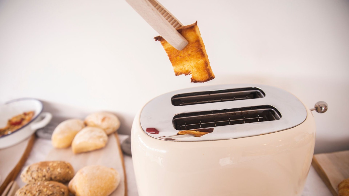 a pair of toasster tongs being used to grab toast out of a toaster