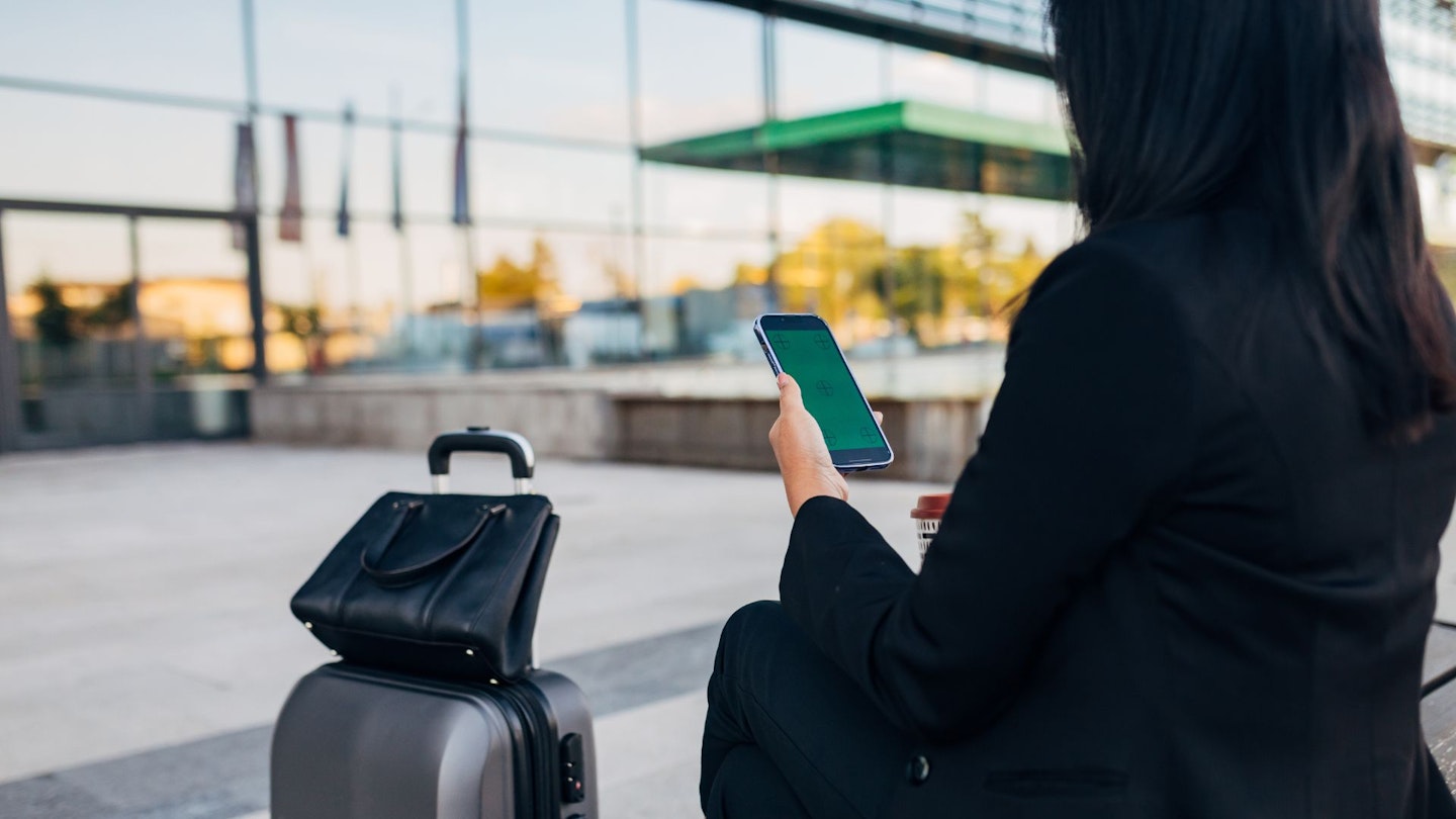 Woman using her phone to loccate her suitcase with a luggage tracker