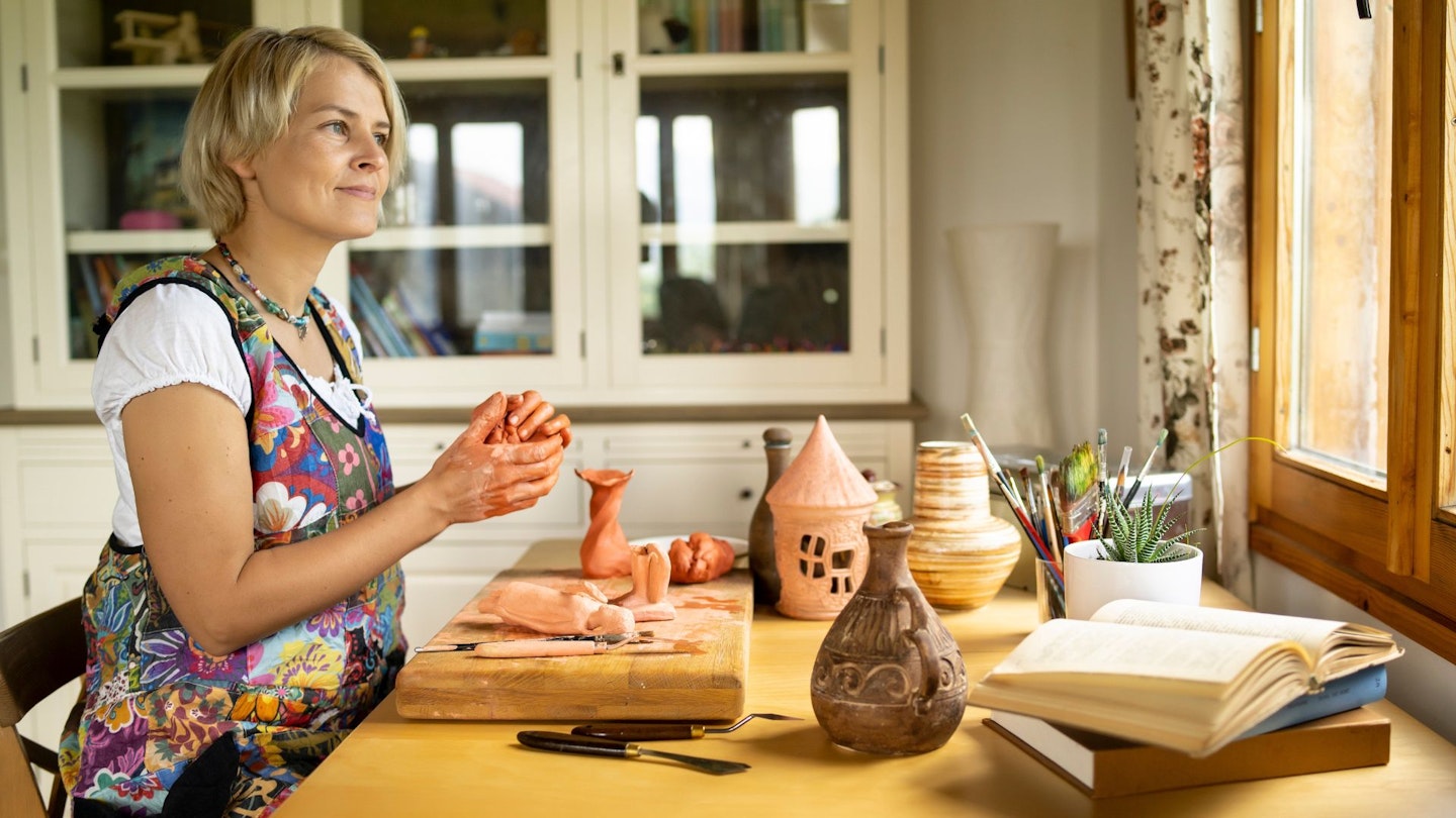 Woman makes clay sculptures at home at her desk
