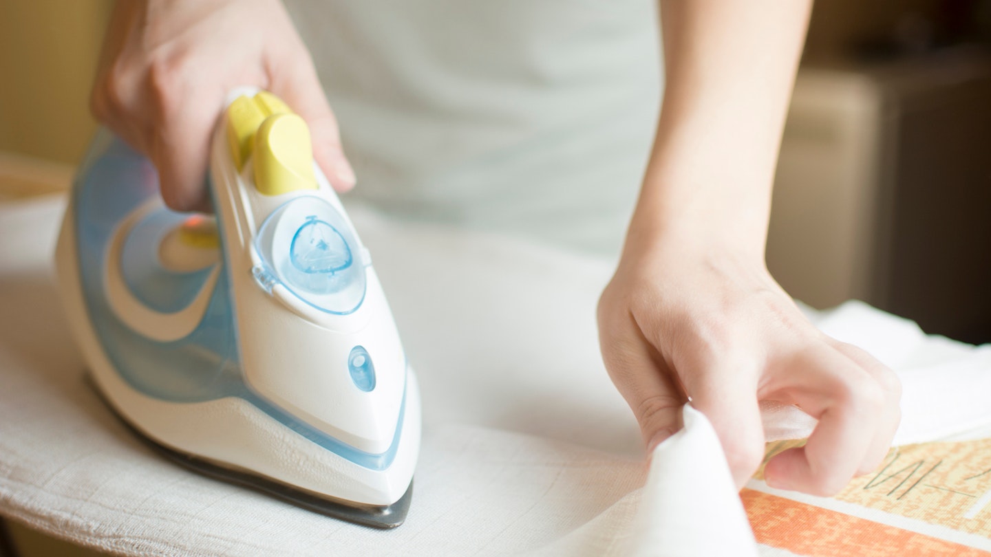 Closeup image of woman hand ironing white cloth.