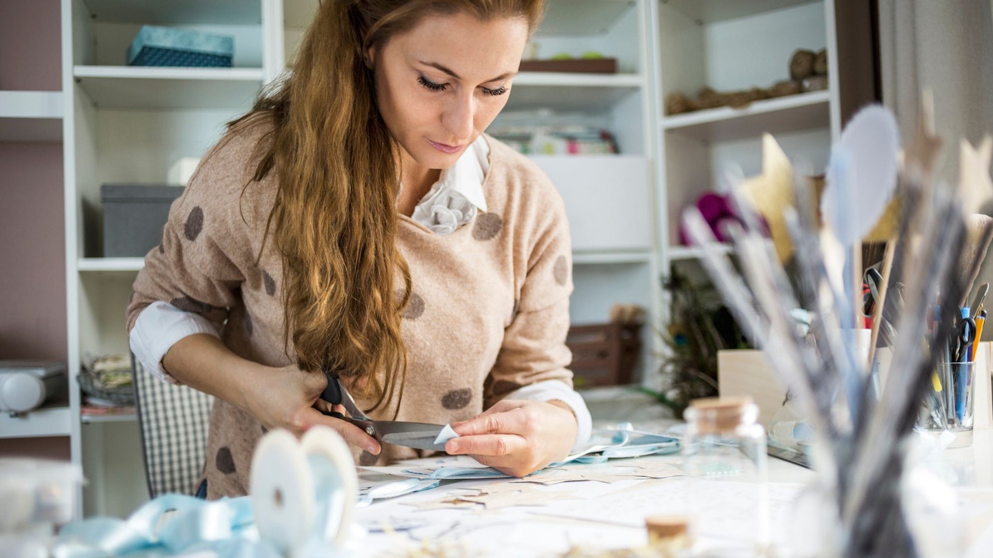 Artisan woman cutting paper in her atelier, small business owner