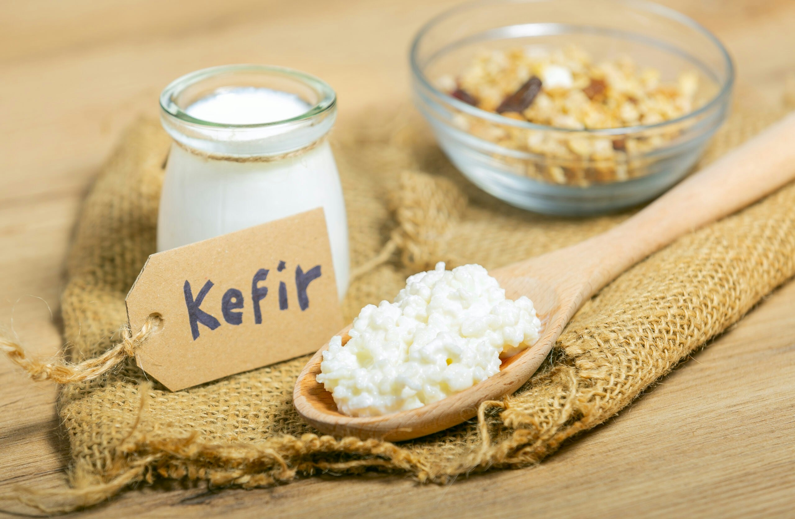 Kefir grains in wooden spoon in front of cups of Kefir Yogurt Parfaits