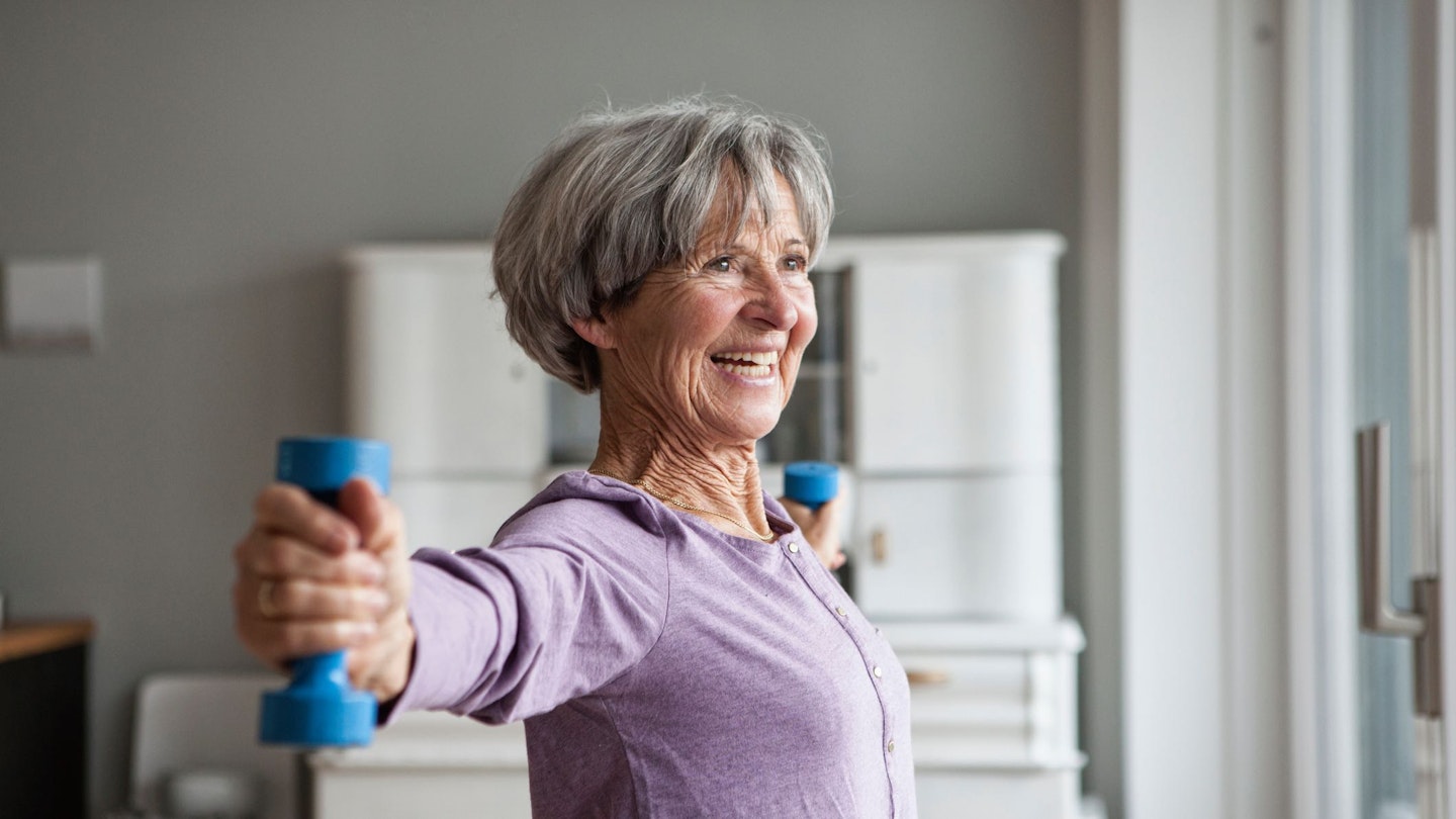 Woman holding a pair of dumbbells at arms length