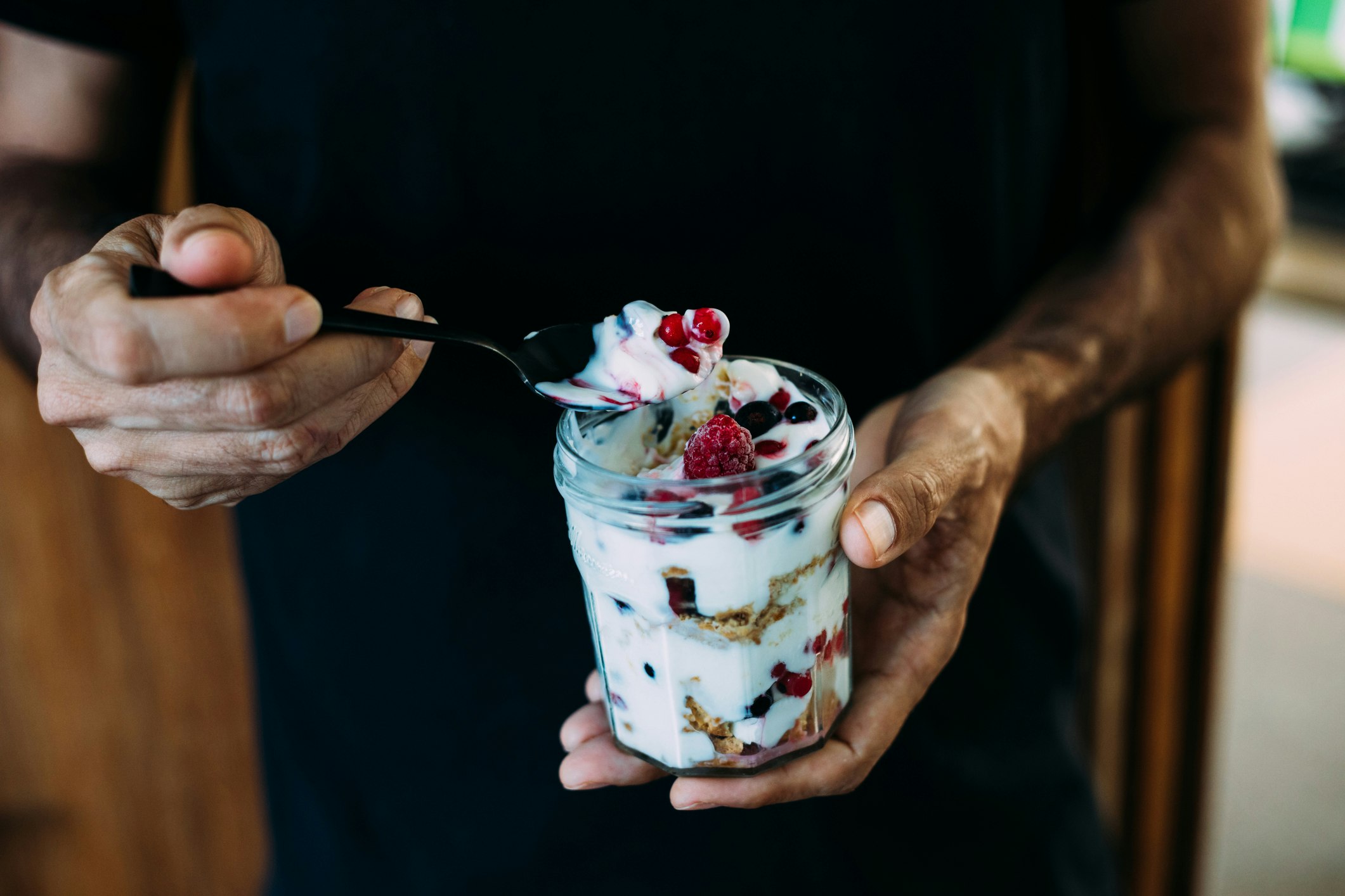 A man holding a jar of yogurt with berries
