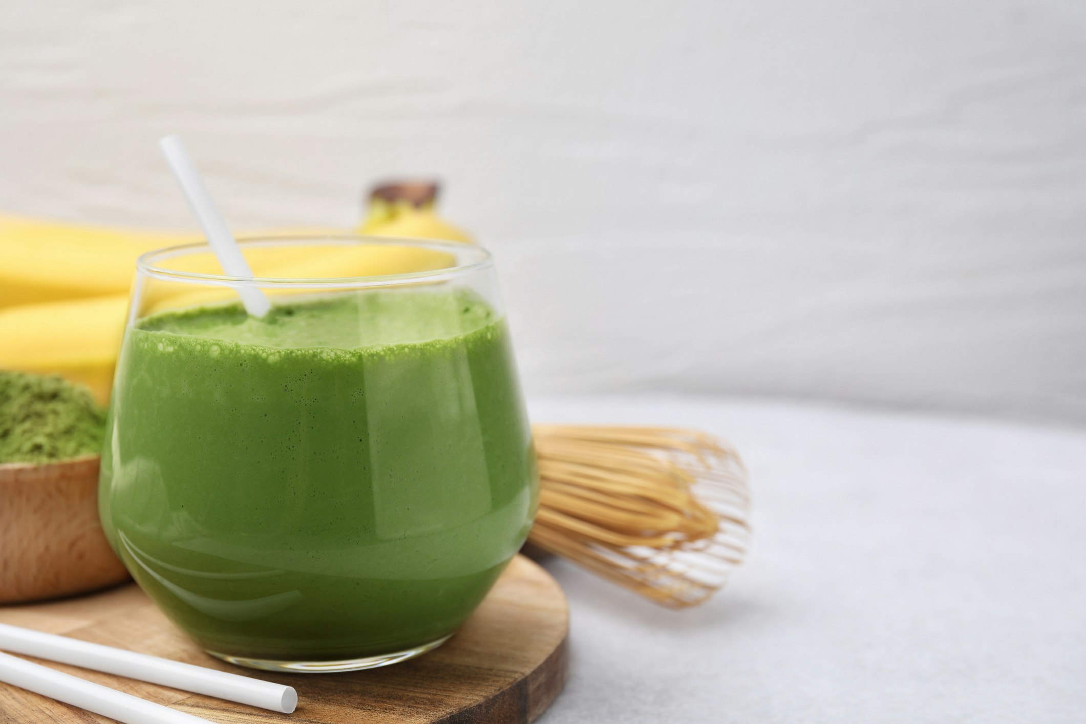 Glass of matcha smoothie on white table